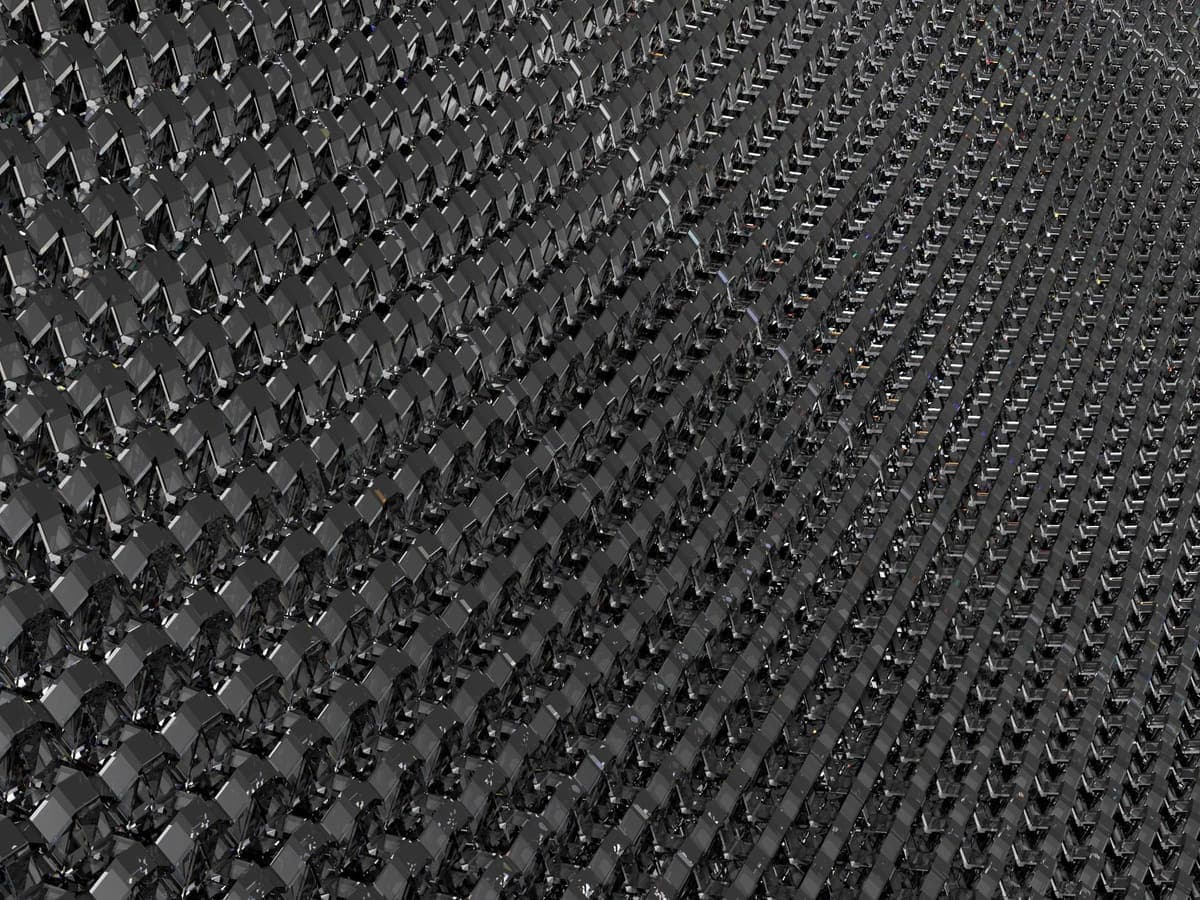 A close view of a black three-dimensional printed lattice filling the frame: rows of small bow-tie cells, each pinched at the waist, receding at an angle.